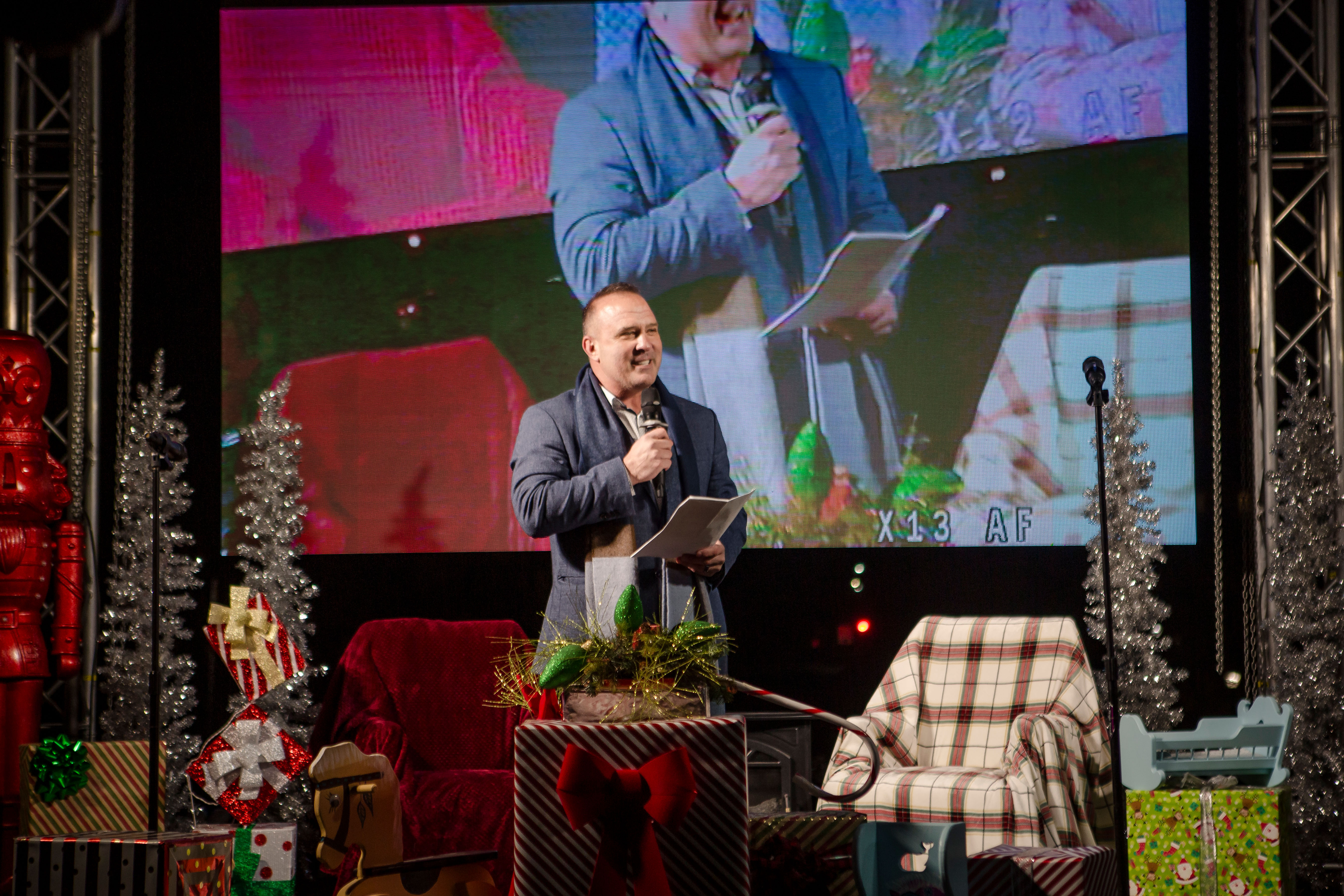 mayor of lees summit on a stage decorated like christmas speaking into a microphone